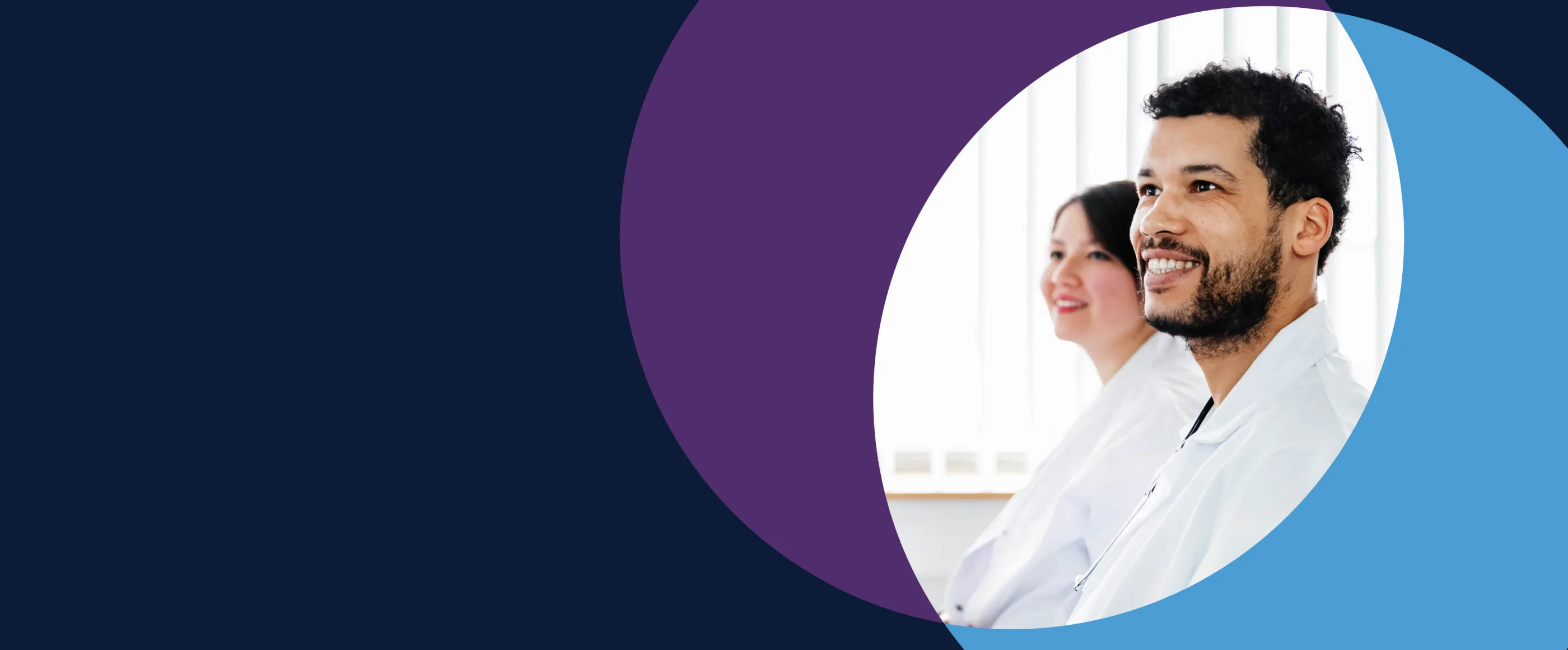 Two medical students smiling in white coats. 
