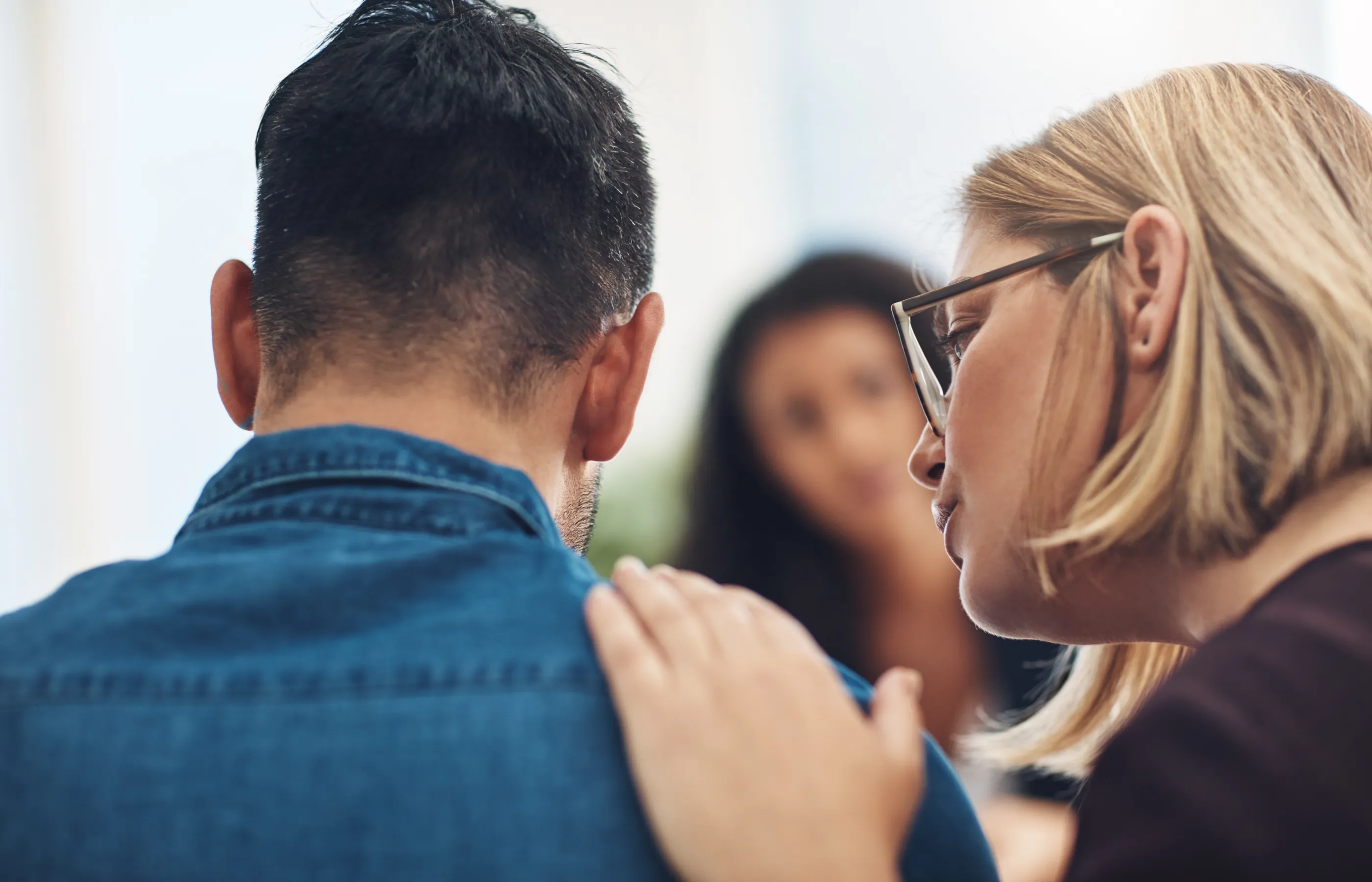 Patient and mental health care provider in office. Provider is touching the shoulder and talking to the patient in support. 