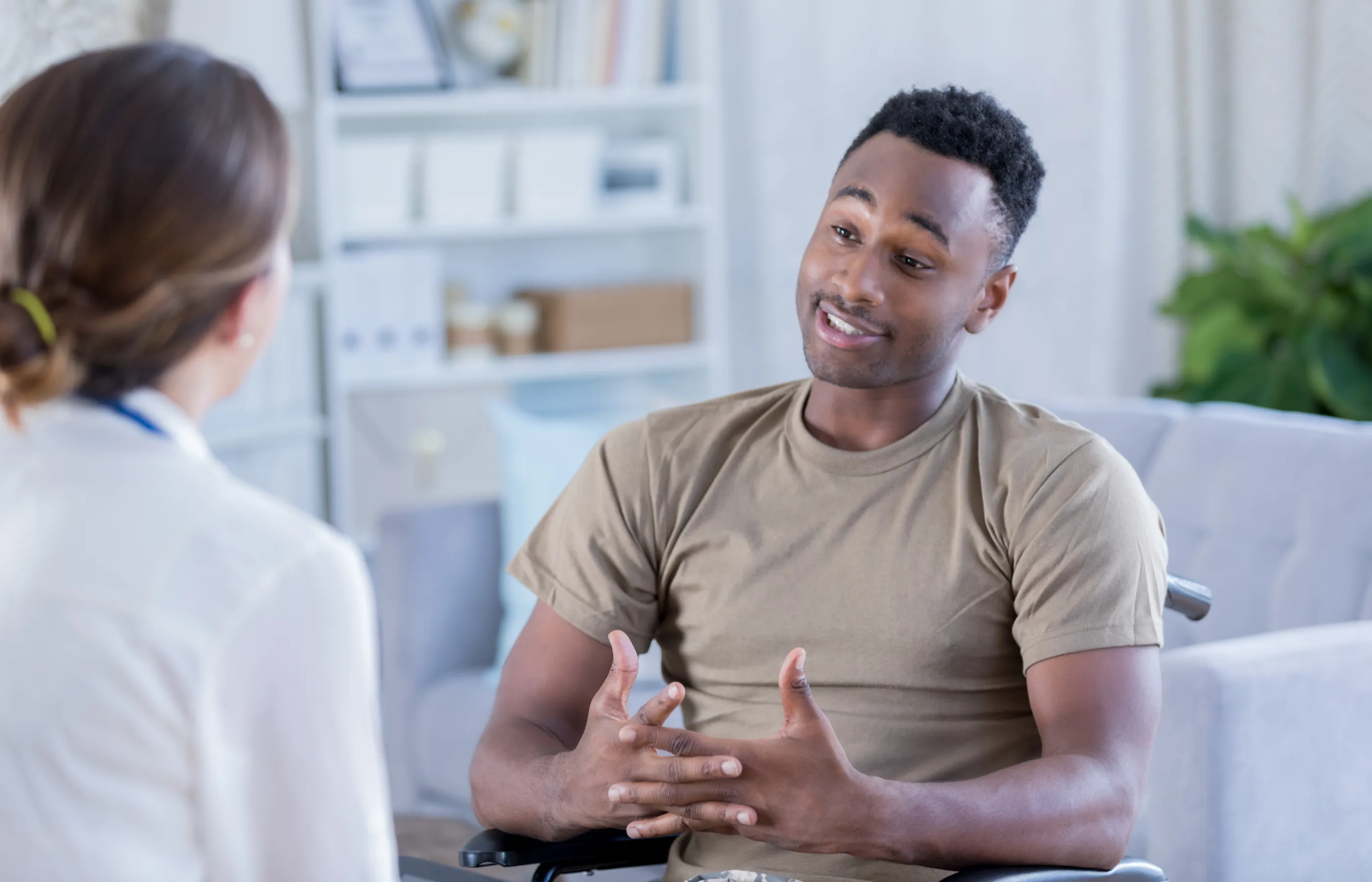A wheelchair bound military patient is talking with his doctor. 