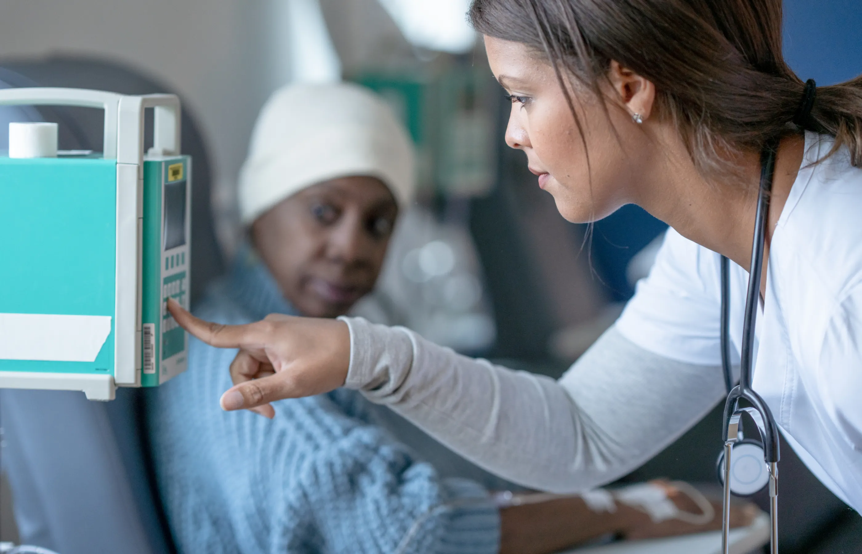 A nurse is standing along side a patient, operating a machine to begin treatment. 