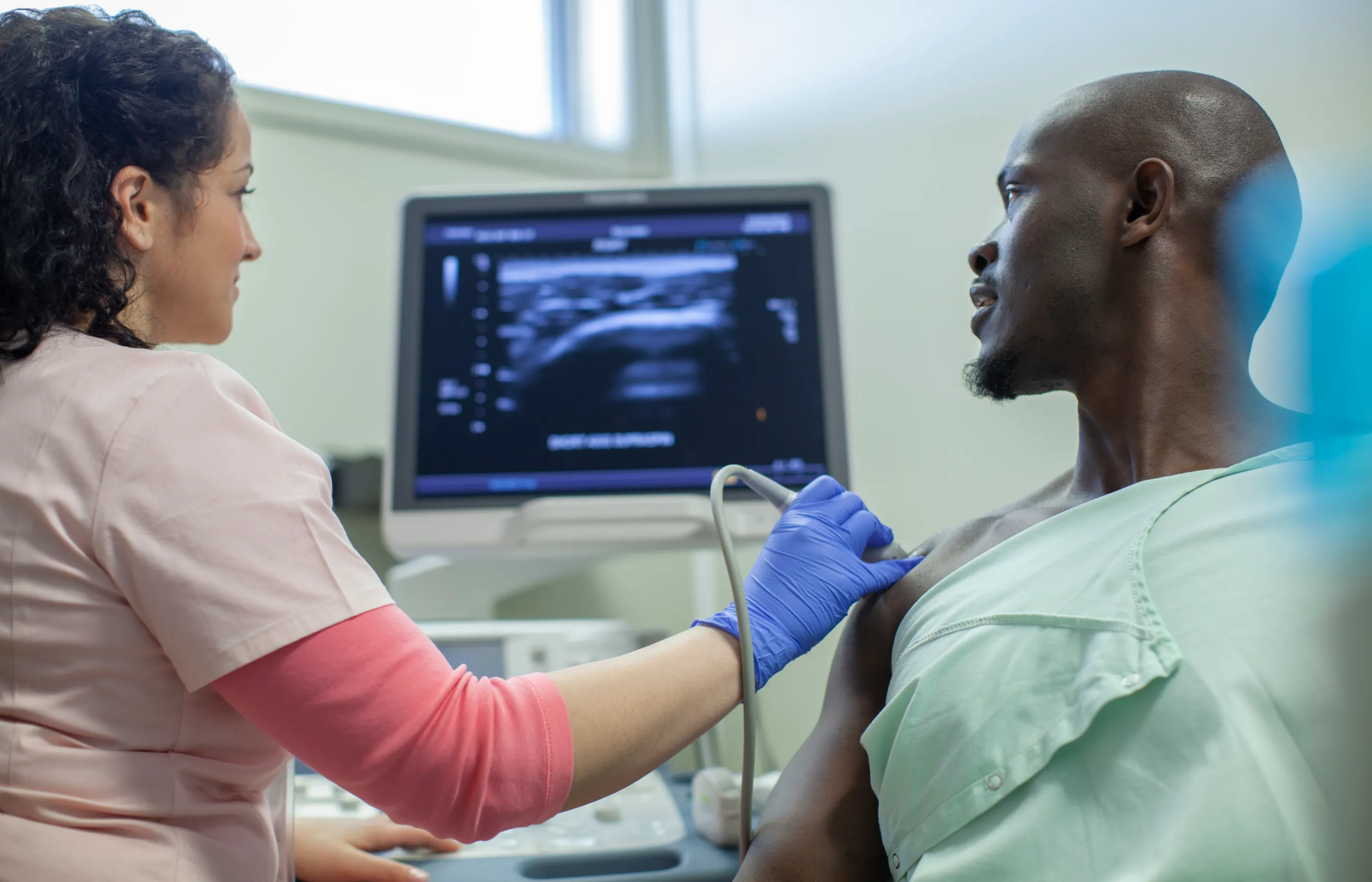 Male patient is observing as a technician performs an ultrasound on his shoulder. 