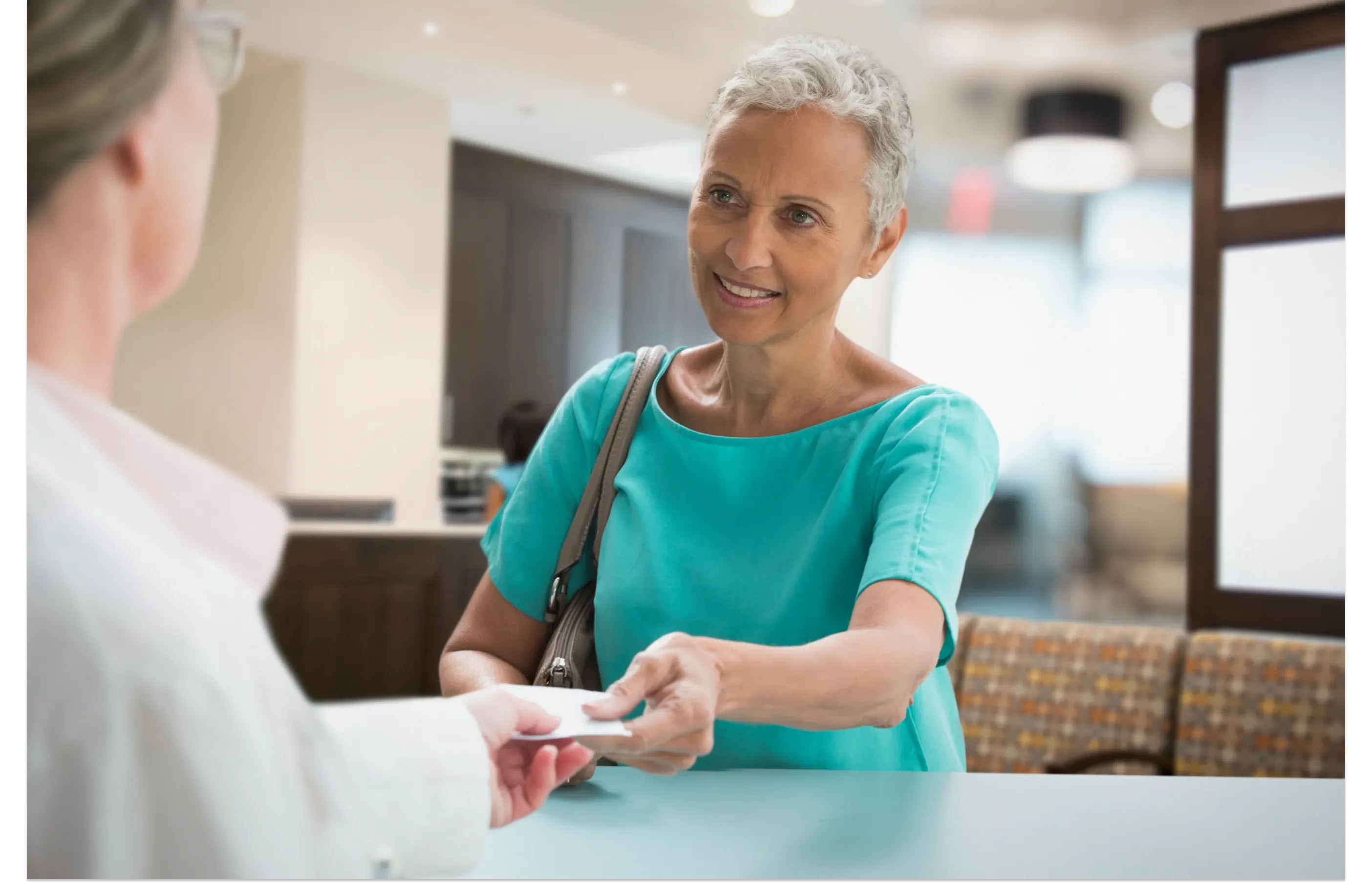 Senior woman at a front desk speaking with a medical professional