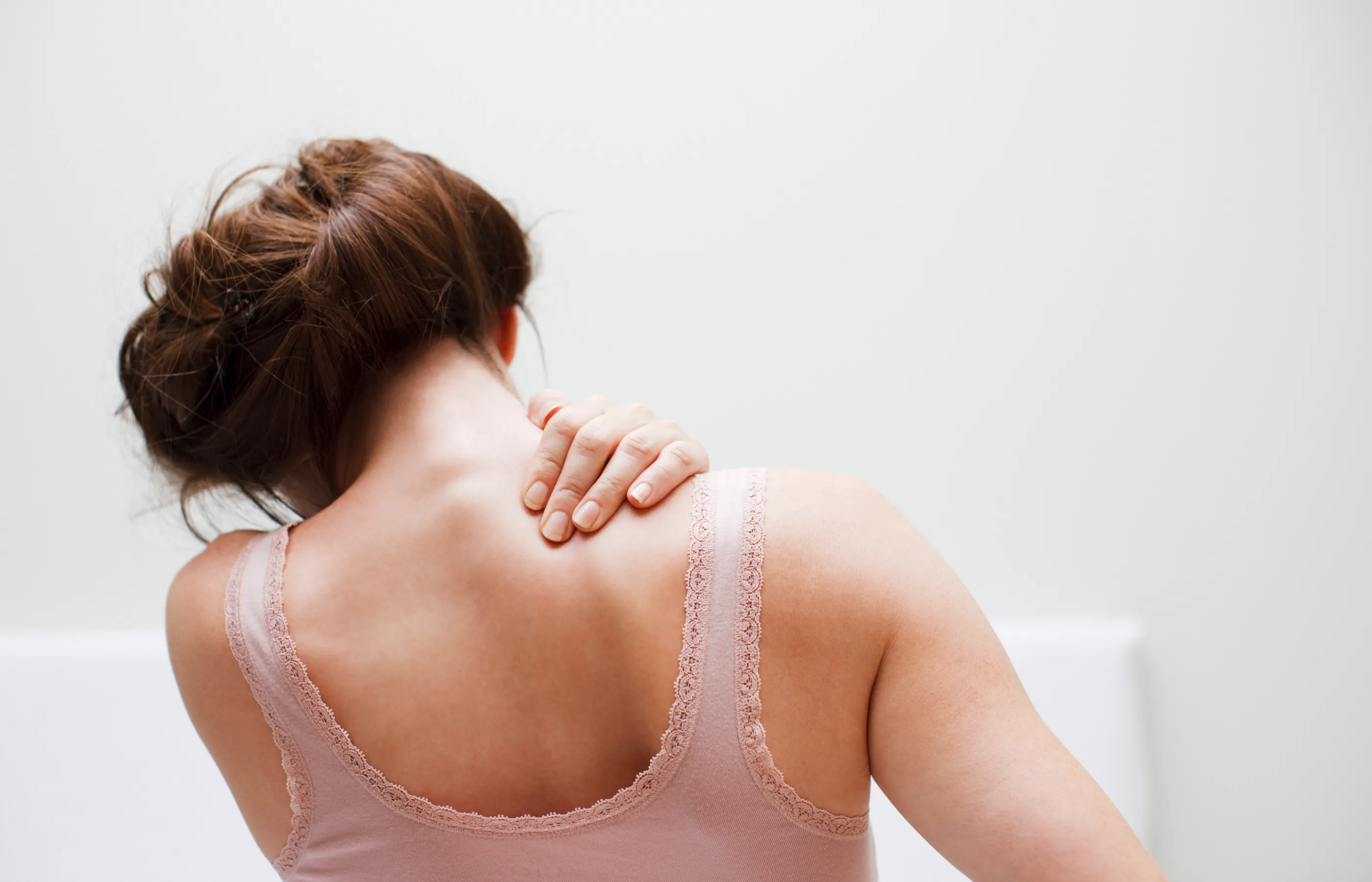 A senior woman is holder her shoulder as she feels pain. 