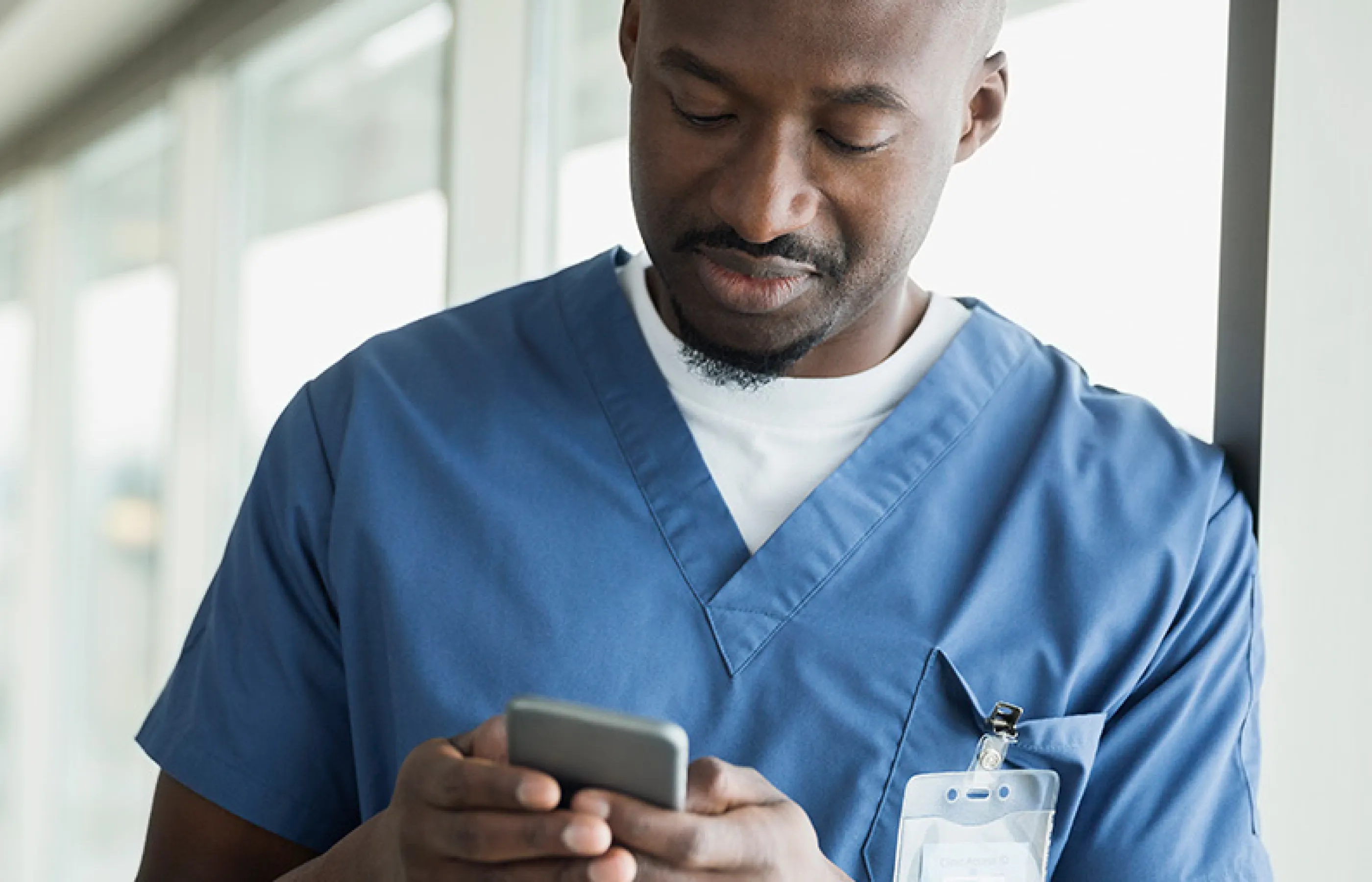Male nurse reads information on his smart phone. 