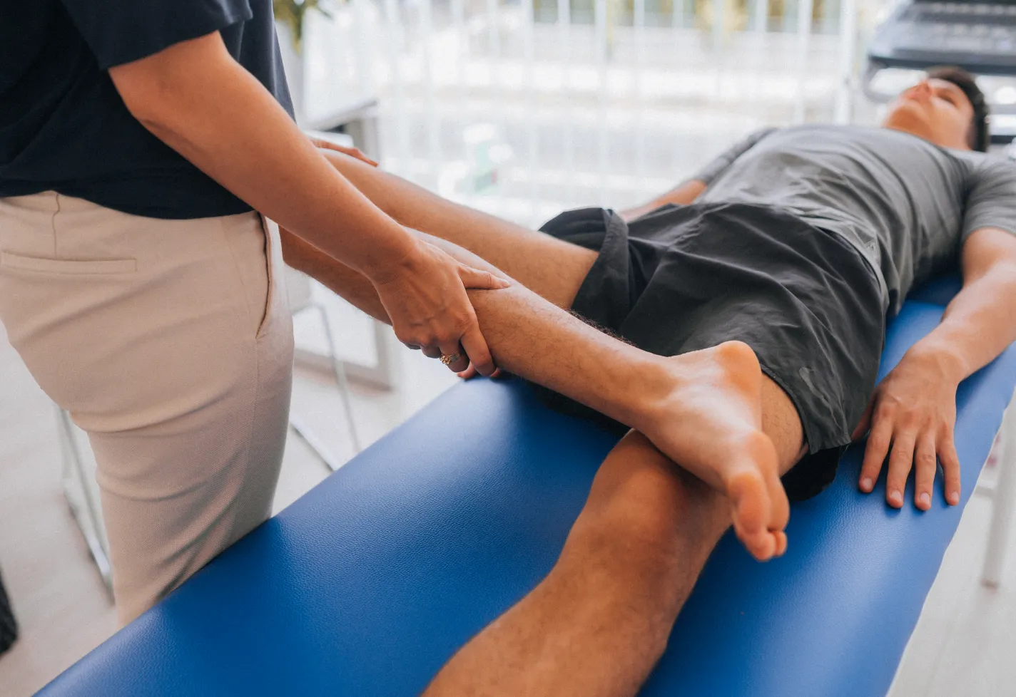 A physical therapist is guiding a patient's knee as they stretch. A physical therapist is guiding a patient's knee as they stretch.