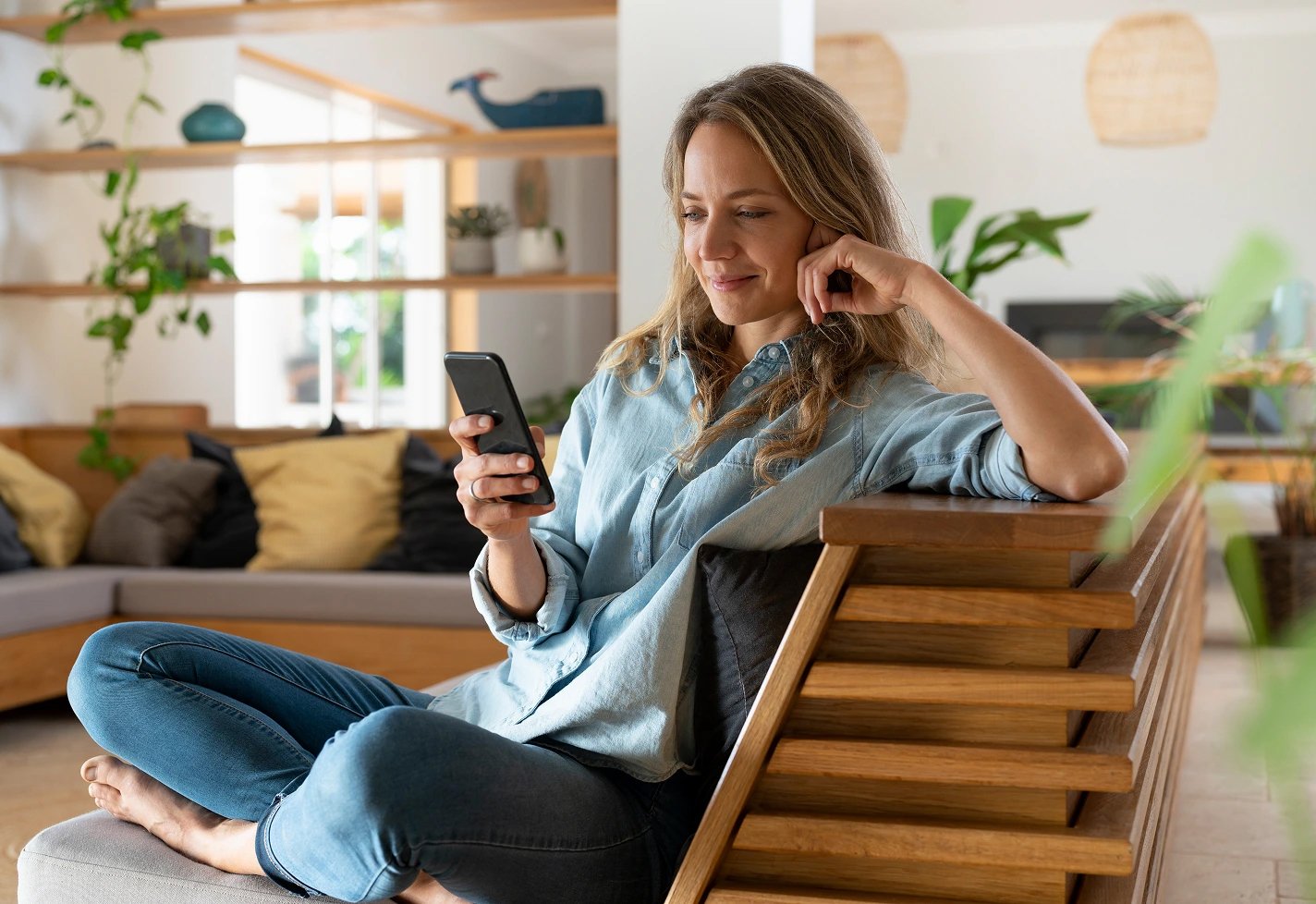 Woman sitting on a wooden couch while looking at her smart phone