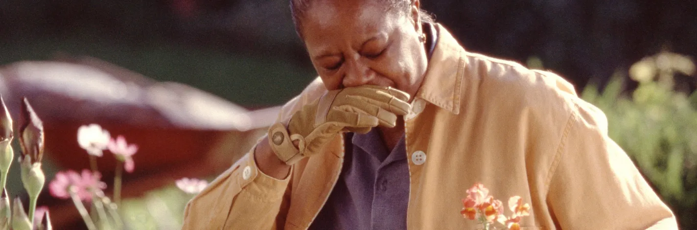 Photo of a woman gardening holding her head in pain
