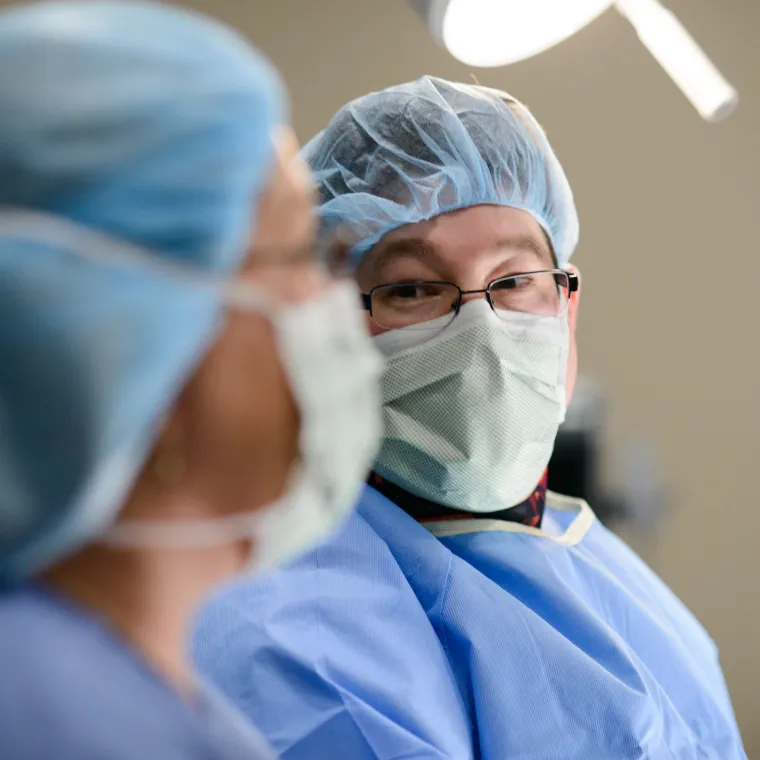A Novant Health team member is dressed in personal protective equipment (PPE) looking over at another team member during surgery.. A Novant Health team member is dressed in personal protective equipment (PPE) looking over at another team member during surgery..