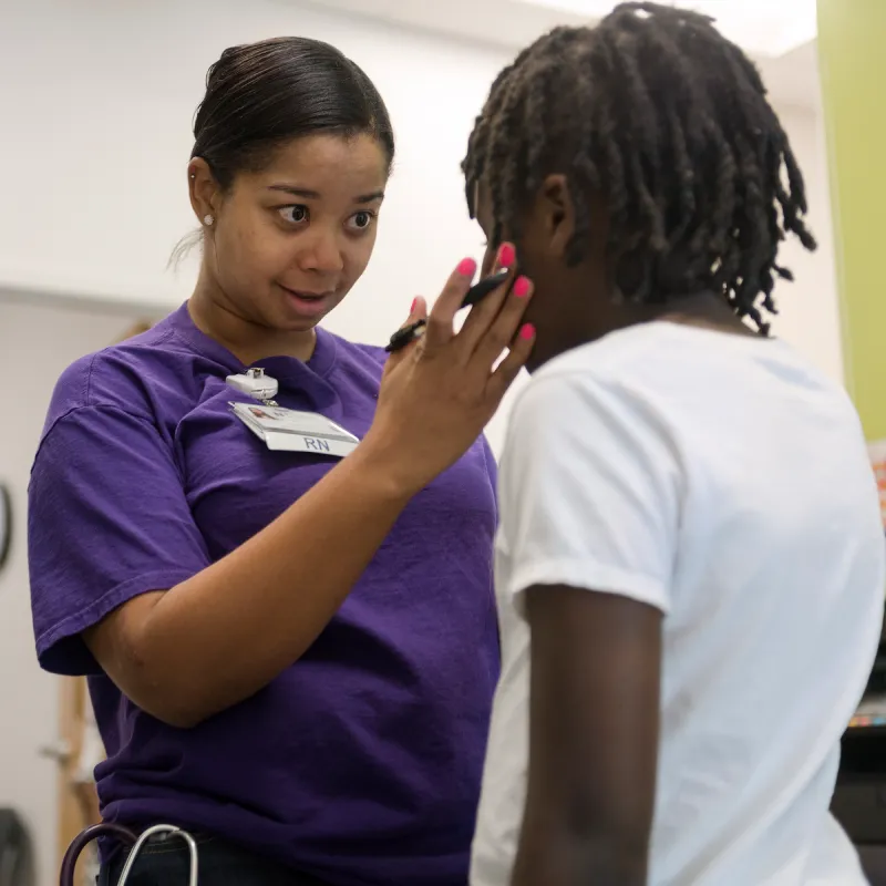 A Novant Health Registered Nurse (RN) is talking with a young child. The RN has a hand placed on the childs face as she talks and looks them in the eye. A Novant Health Registered Nurse (RN) is talking with a young child. The RN has a hand placed on the childs face as she talks and looks them in the eye.