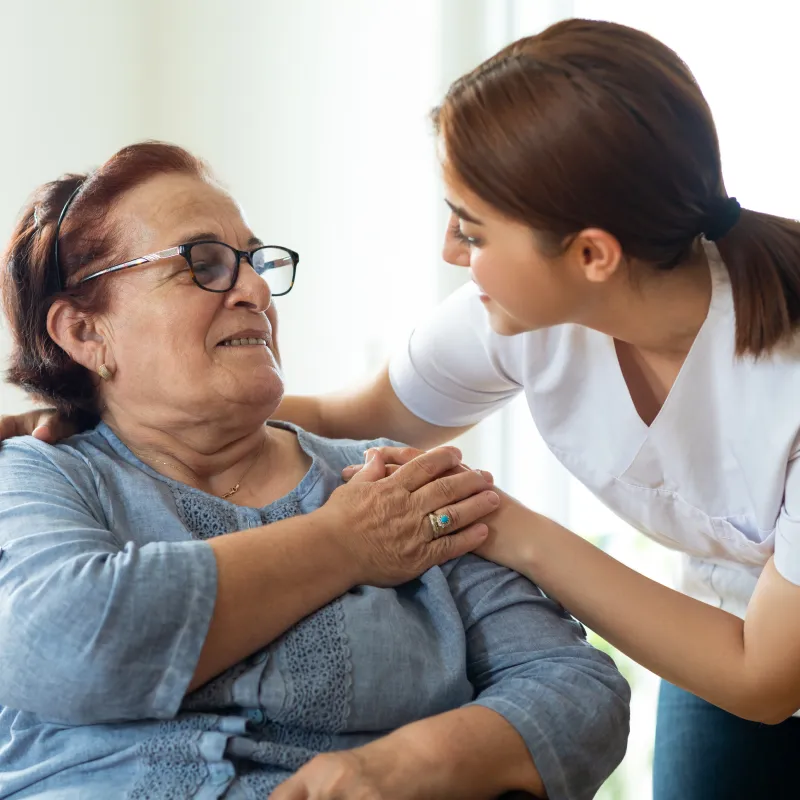 A nurse is leaning over talking with a senior woman patient. A nurse is leaning over talking with a senior woman patient.